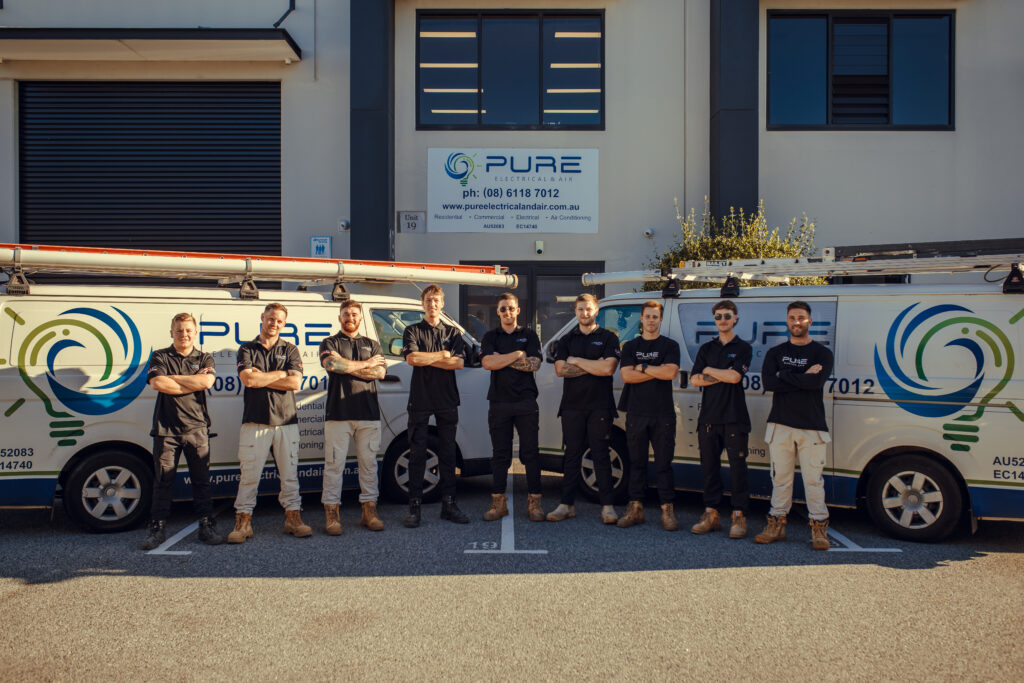 Tradies standing out the front of their office, with two branded vans on the sides